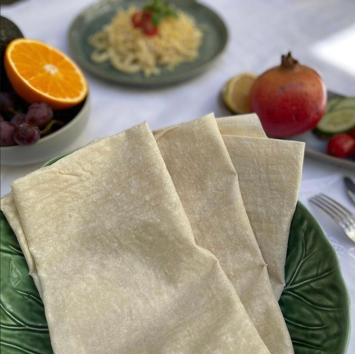 Folded sheets of Böreklik Yufka on dark wood with spilled flour